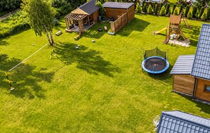 Ein gepflegter Garten mit Trampolin, Holzspielhaus und Schaukel.