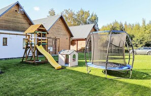 Ein Spielplatz mit Rutsche, Schaukel und einer kleinen Spielhütte.