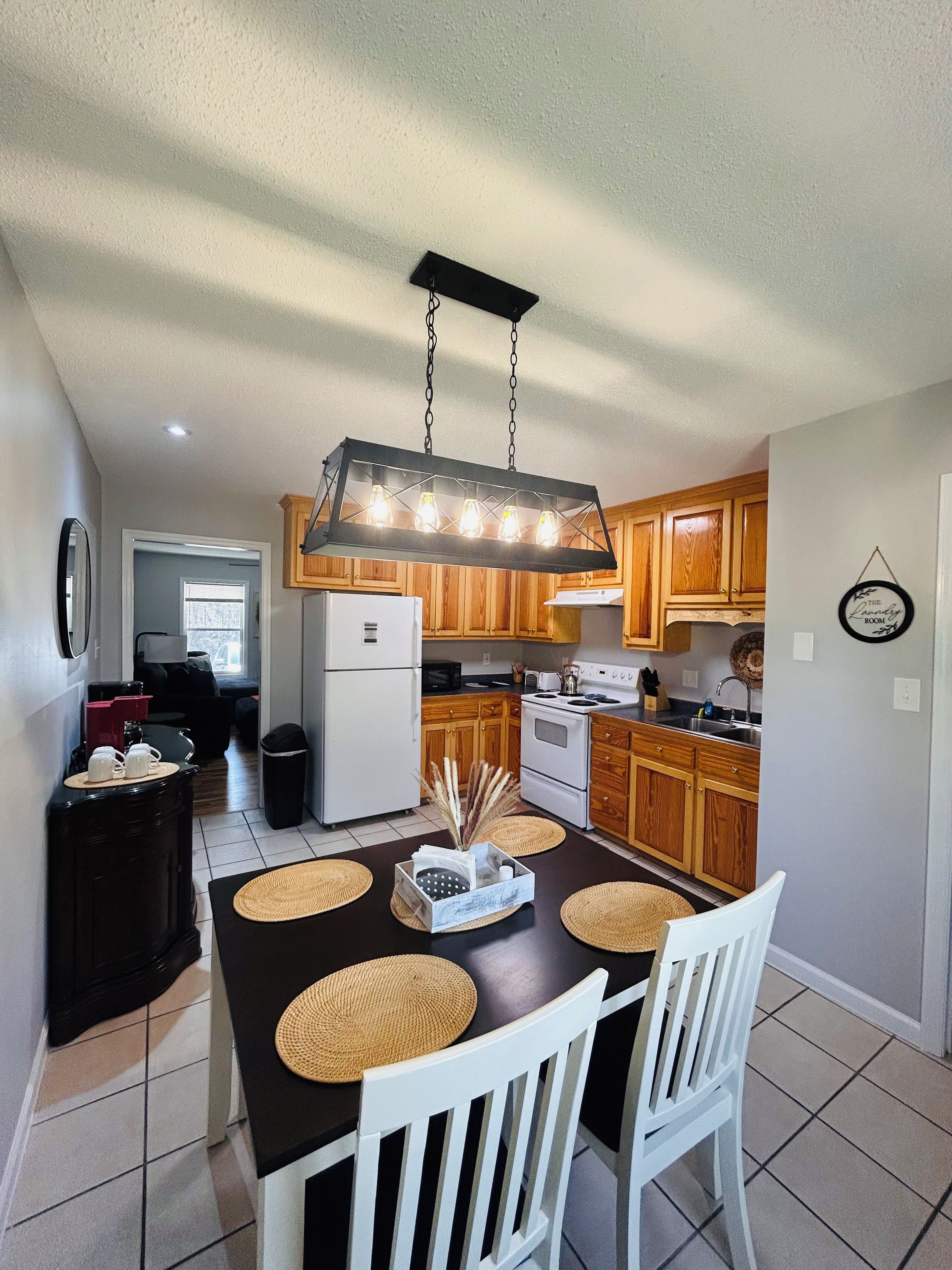 Una cocina moderna con armarios de madera, una isla central con sillas y una lámpara colgante.