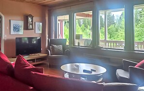 Ein Wohnzimmer mit Fernseher, einem runden Couchtisch und einer Couch.