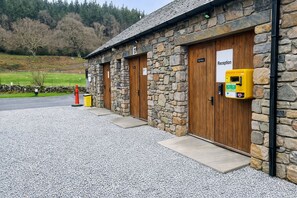 Un edificio de piedra con puertas de madera, un cartel de recepción y un teléfono amarillo de emergencia.