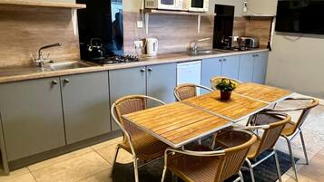 A compact kitchen with a dining table, chairs, and basic appliances.