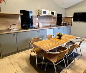 A compact kitchen with a dining table, chairs, and basic appliances. - Torrent Walk Bunkhouse  (Dolgellau)
