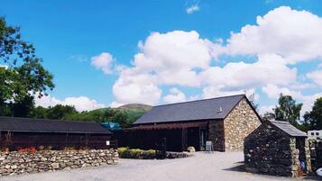 A stone building with a sloped roof, surrounded by a gravel area and a stone wall.
