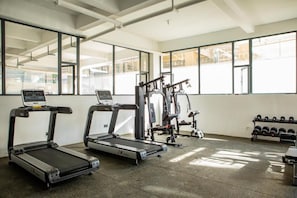 Ein Fitnessstudio mit Laufbändern, Kraftgeräten und Kurzhanteln.