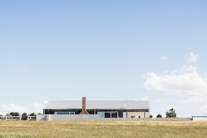 A modern building with a metal roof, a brick chimney, and a fenced perimeter.
