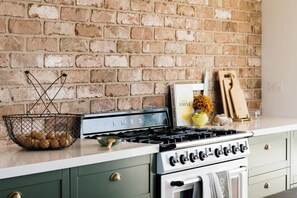 A kitchen with a brick wall, a stove, and a basket of eggs. - Carrick Farmhouse Luxury Retreat (Carrick)