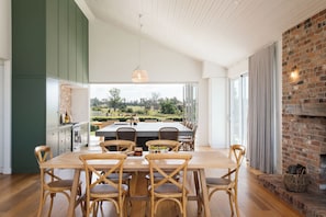A dining area with a large table, multiple chairs, and a view of the outdoors.