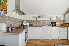 A modern kitchen with white cabinetry, a wooden countertop, and a built-in stove. - Host Stay Indigo Snug (Cromer)