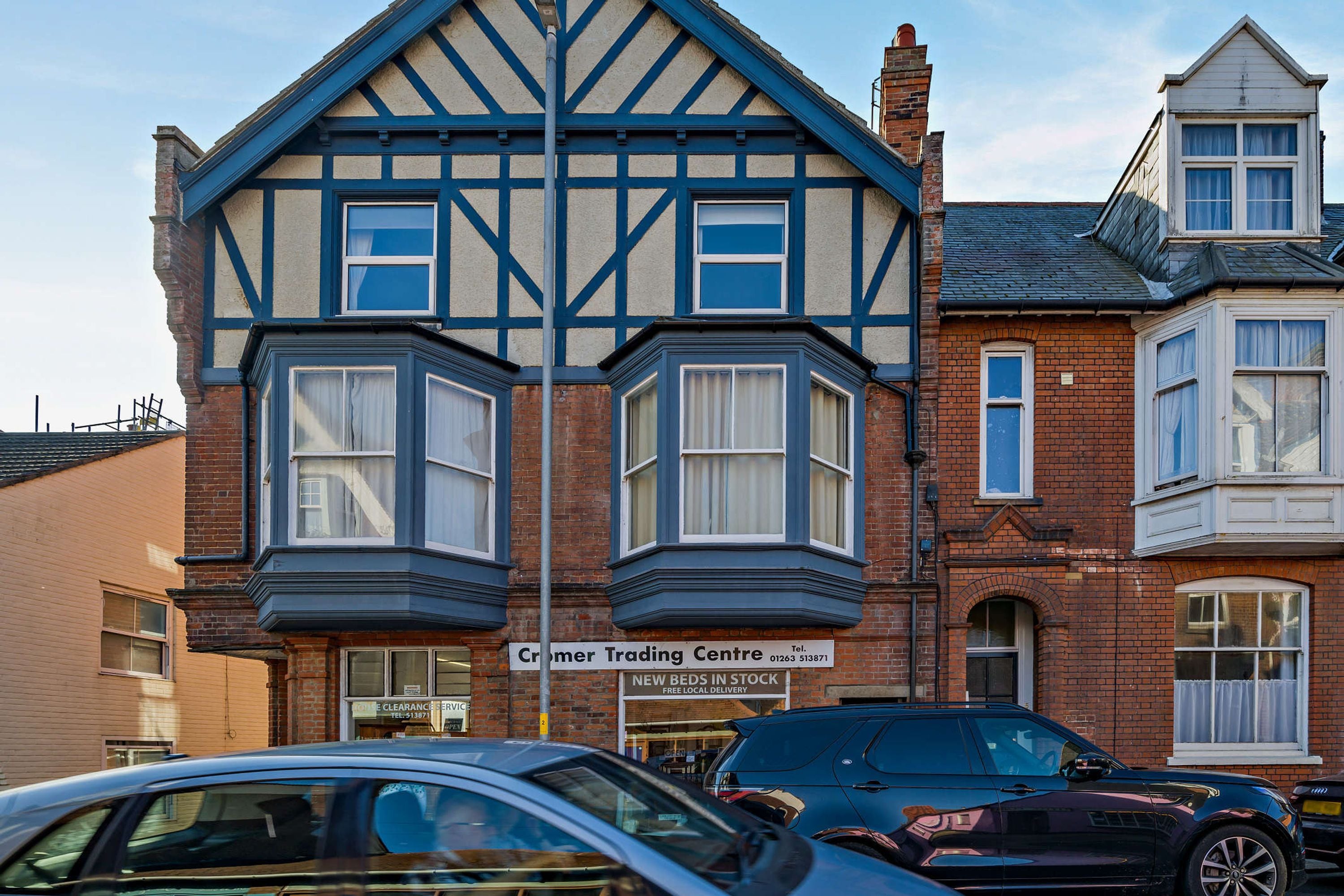 A building with a corner bay window, a sign for a trading center, and a car parked in front.