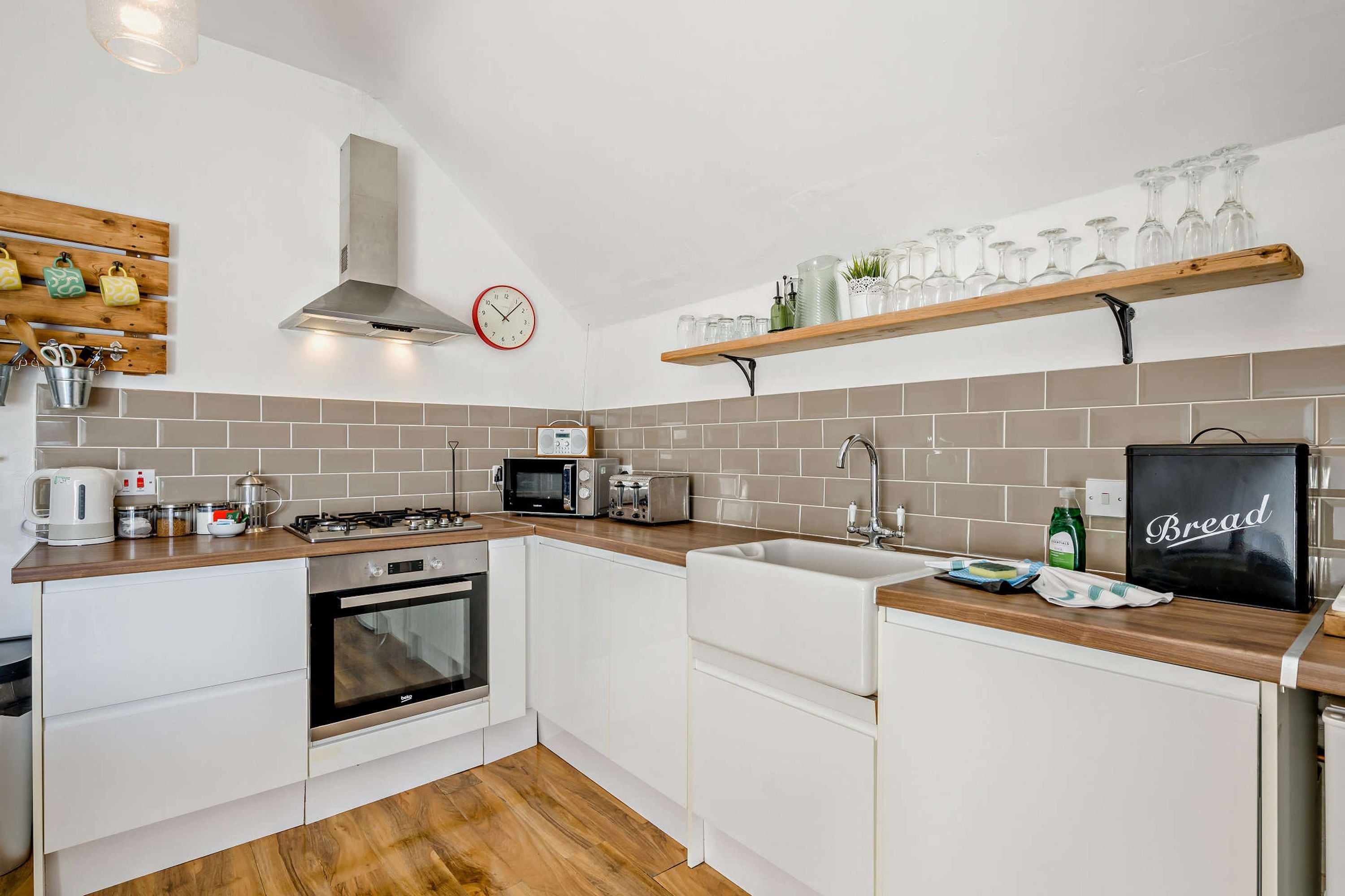 A modern kitchen with white cabinetry, a gas stove, a microwave, a toaster, and a bread box.