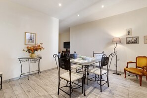 A dining area with a table and chairs, a vase with flowers, and a lamp. - Holiday Home 'La Bergerie' with Private Terrace, Private Garden and Air Conditioning (Caux)