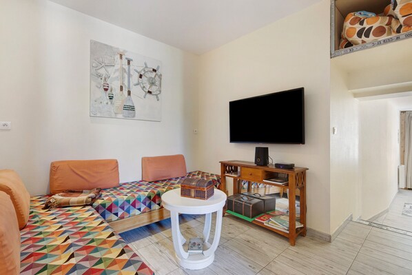Ein Wohnzimmer mit einer Couch, einem Couchtisch, einem Fernseher und einem Gemälde an der Wand.