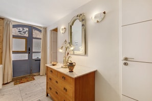 A room with a wooden dresser, a mirror, and a door with a blue and white pattern. - Holiday Home 'La Bergerie' with Private Terrace, Private Garden and Air Conditioning (Caux)