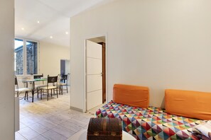 A room with a bed, a dining area, and a view of a stone building. - Holiday Home 'La Bergerie' with Private Terrace, Private Garden and Air Conditioning (Caux)