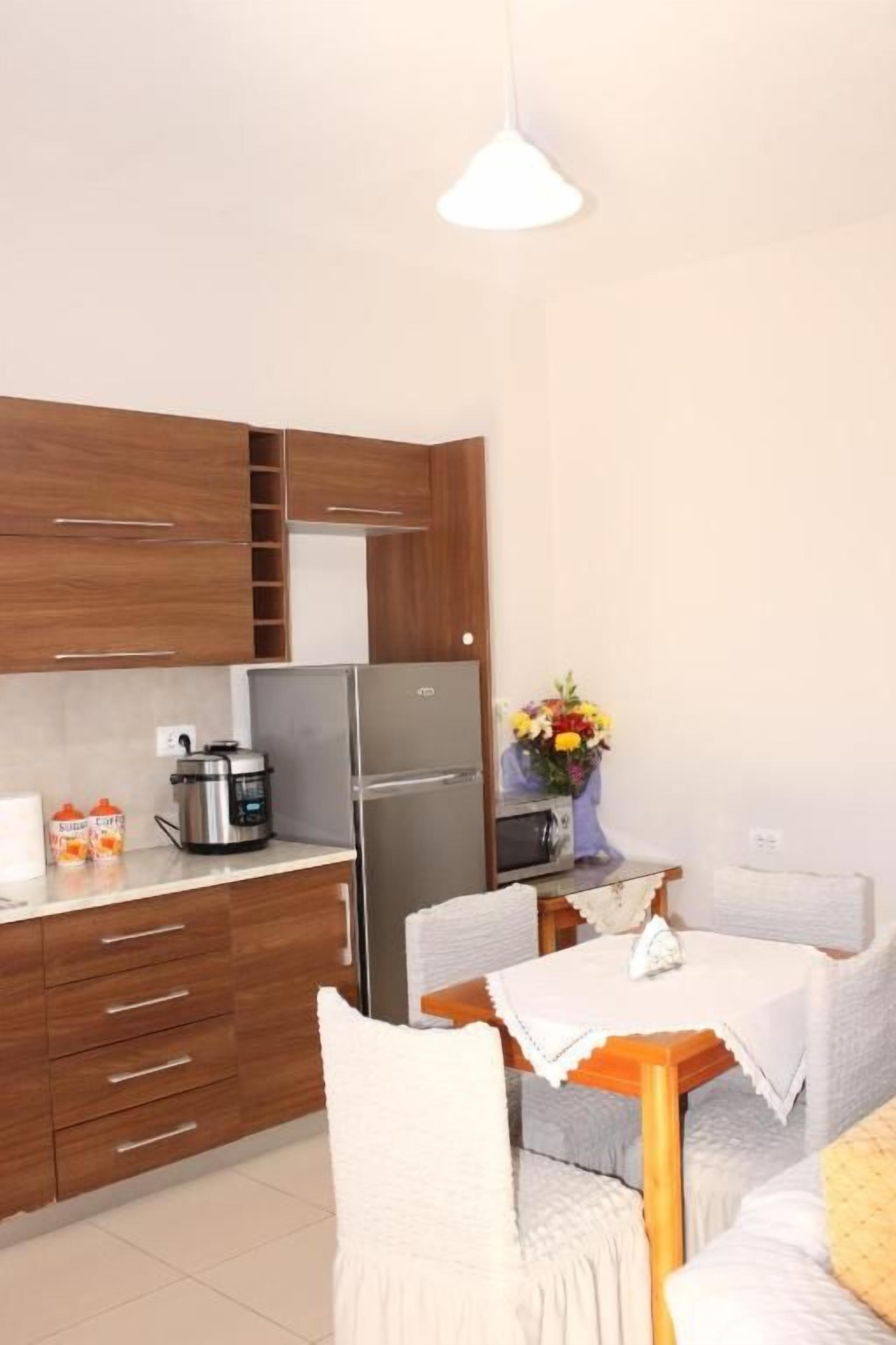 Cocina compacta con armarios de madera, un refrigerador y una mesa de comedor con sillas.