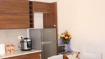 Cocina compacta con armarios de madera, un refrigerador y una mesa de comedor con sillas.