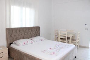 A bedroom with a bed, a bedside table, a chair, and a window with curtains.