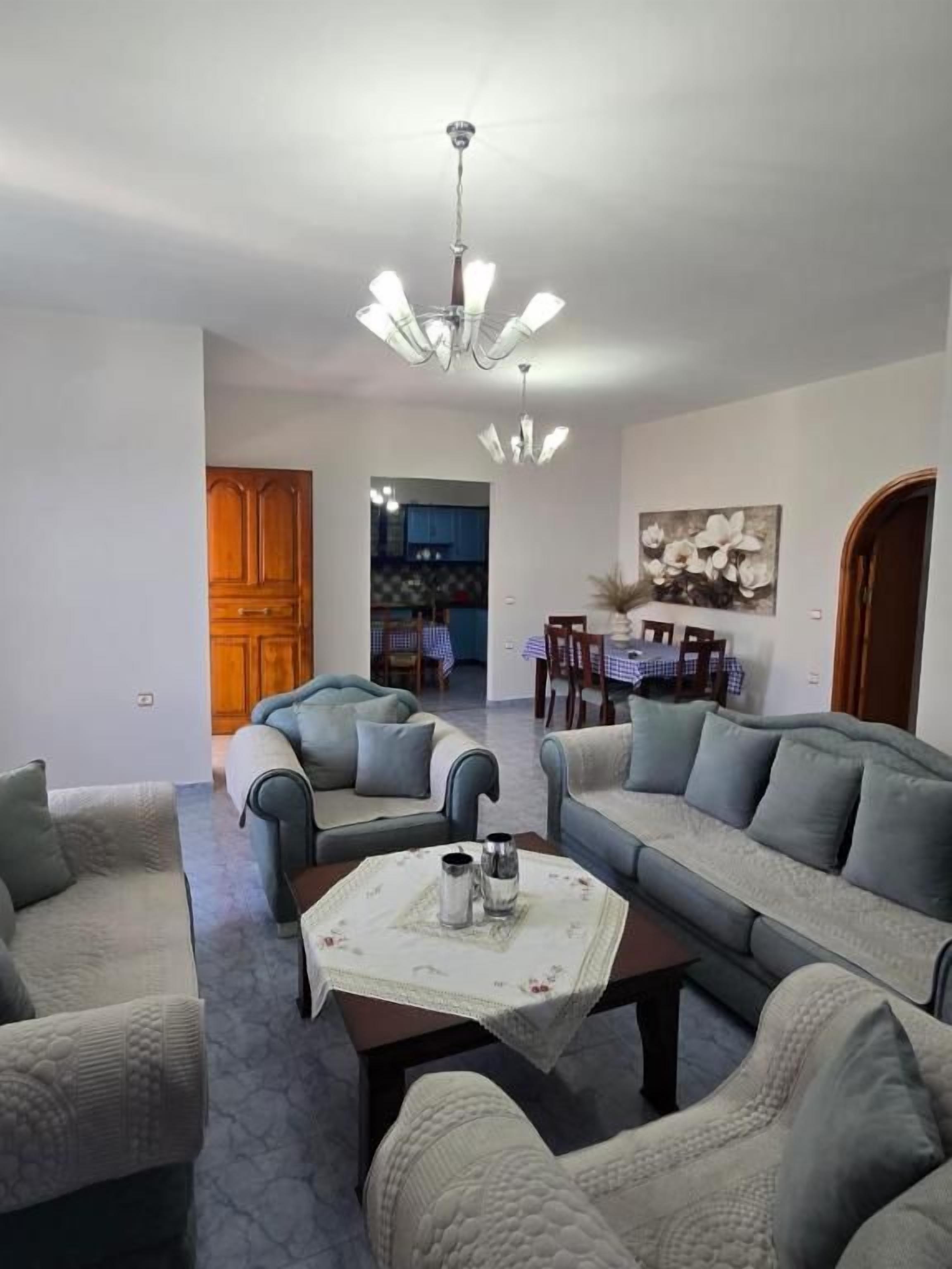 A living room with a sofa set, a coffee table, and a chandelier.