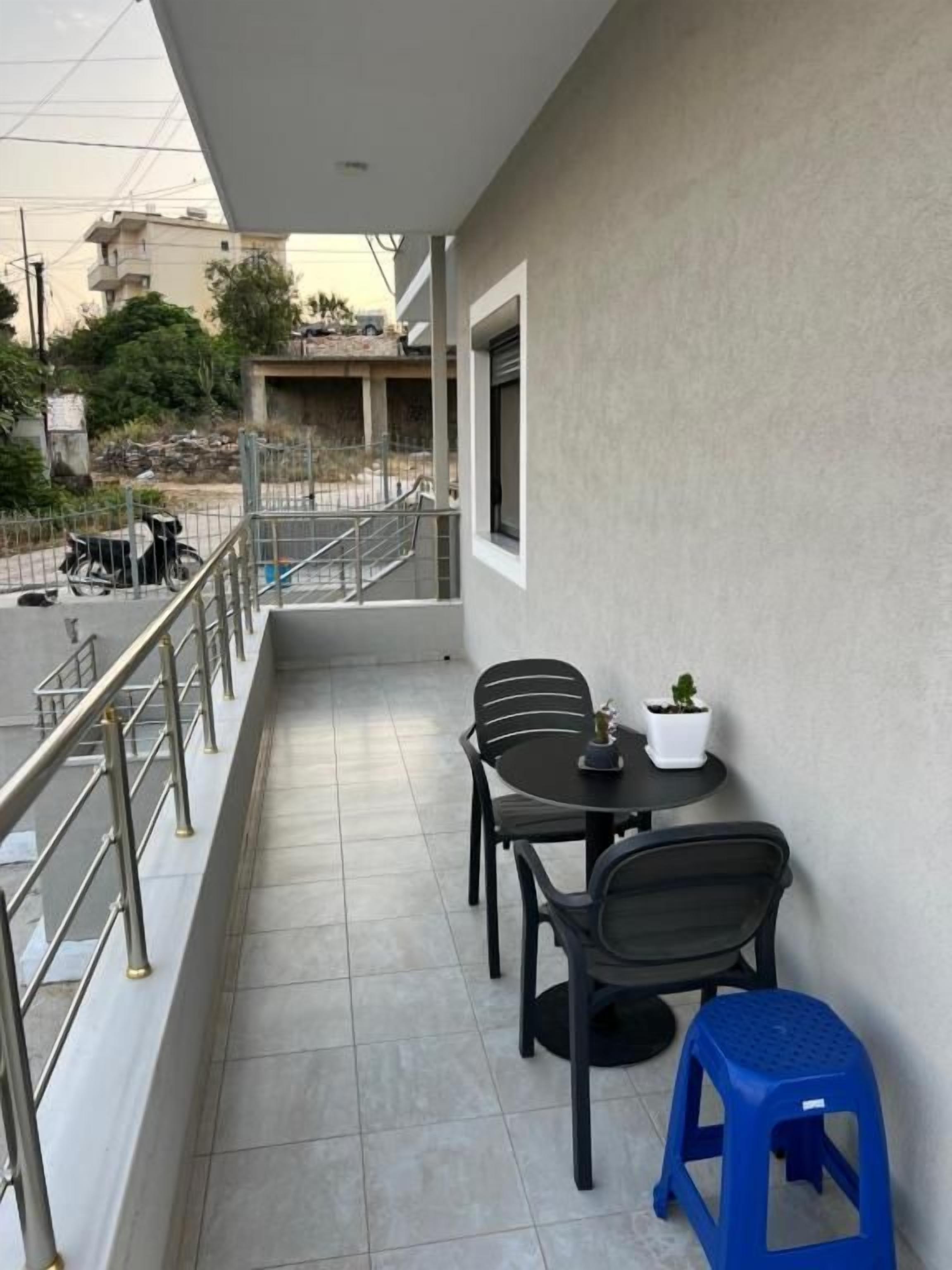 A balcony with a table and chairs, a small stool, and a potted plant.