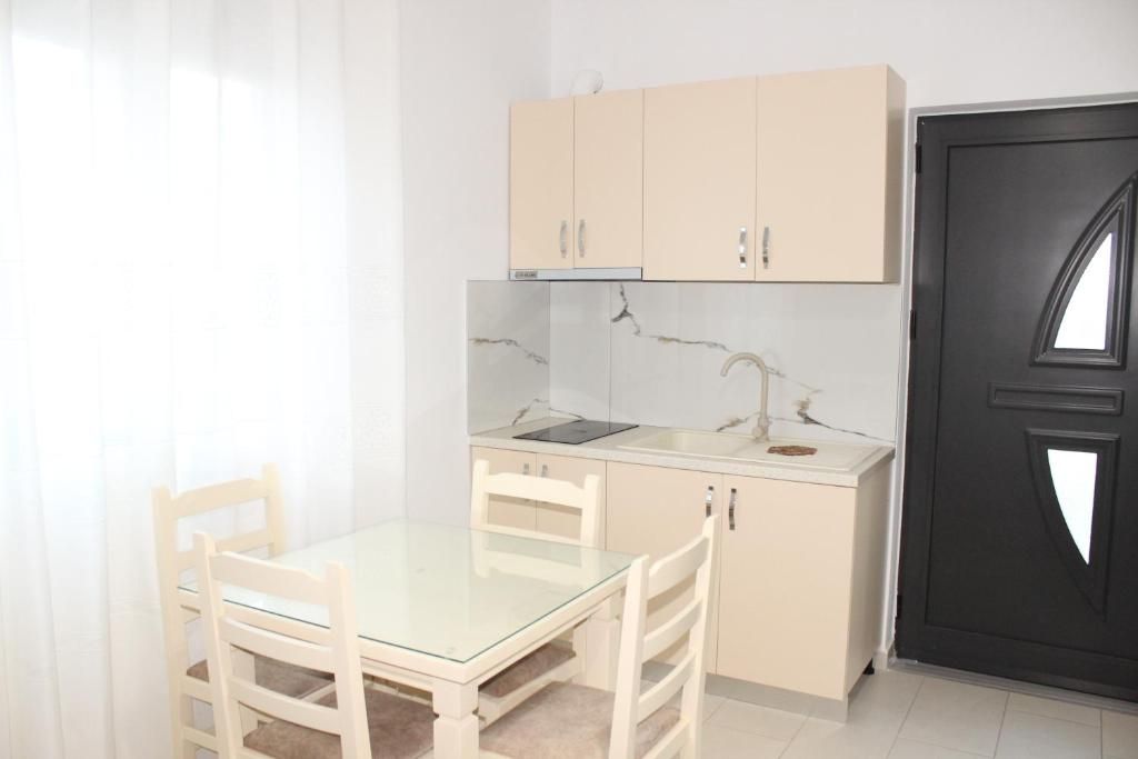 A compact kitchen with a single countertop, a sink, and cabinets. There is a dining table with chairs.
