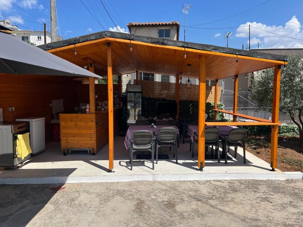Une terrasse extérieure avec une table et des chaises en bois, un barbecue et un espace abrité avec une table et des chaises.