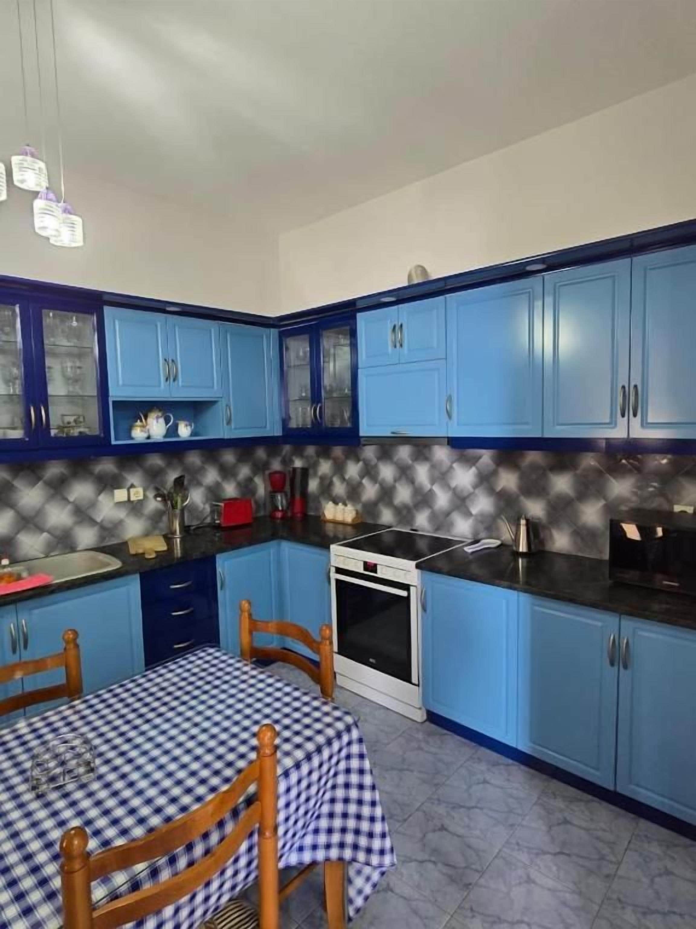 A kitchen with blue cabinets, a checkered tablecloth, and a white oven.