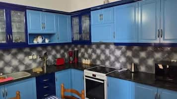 Una cocina con armarios azules, mantel a cuadros y horno blanco.
