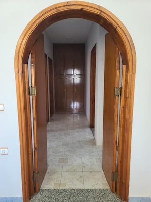 Un pasillo con un marco de puerta de madera que da a una habitación con piso de baldosas.