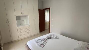 Un dormitorio con cama, armario y puerta que da a otra habitación.