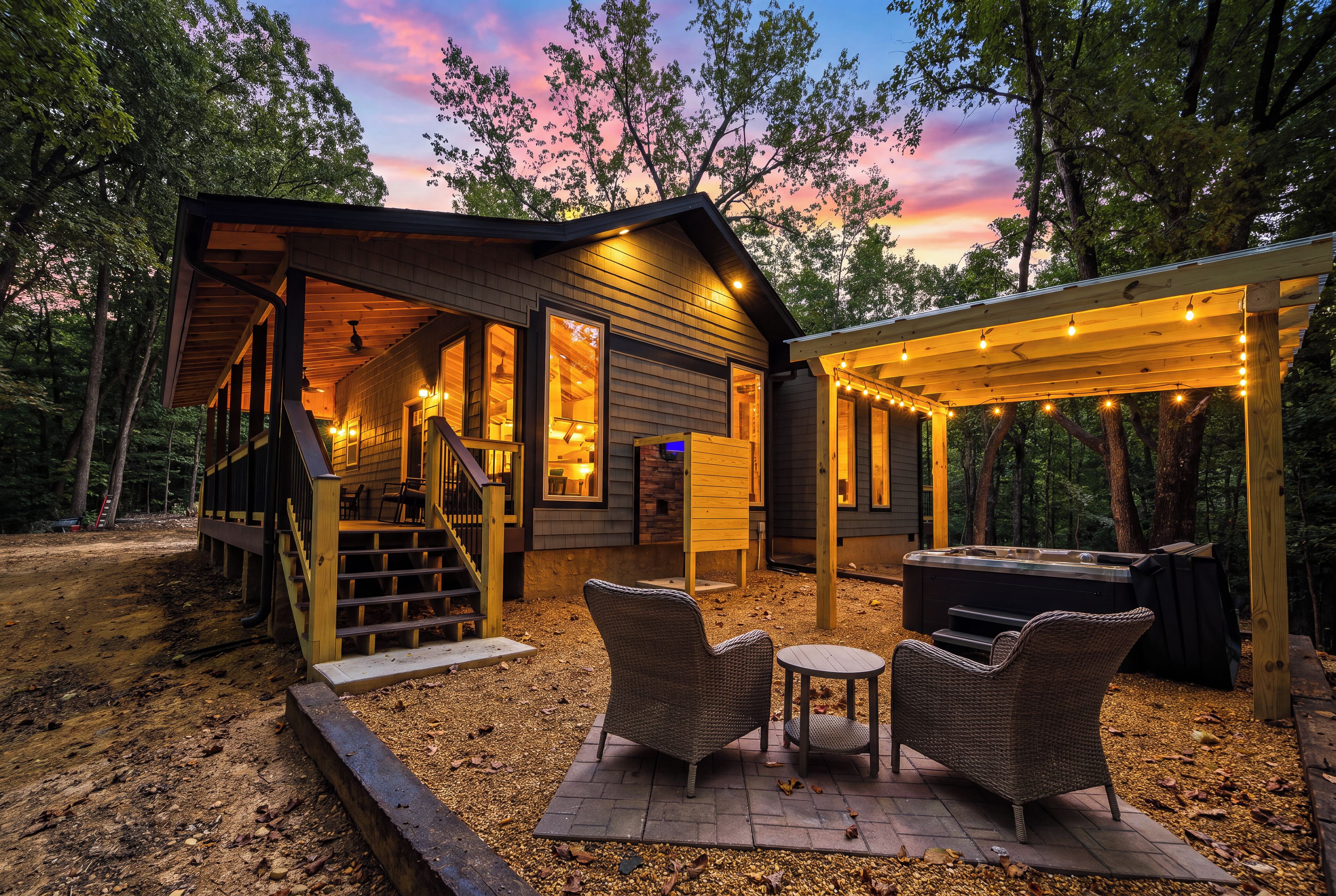 Una cabaña de madera con un porche cubierto, mobiliario exterior y un jacuzzi.