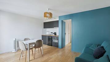 A modern apartment with a dining area, kitchenette, and a teal-colored living space.