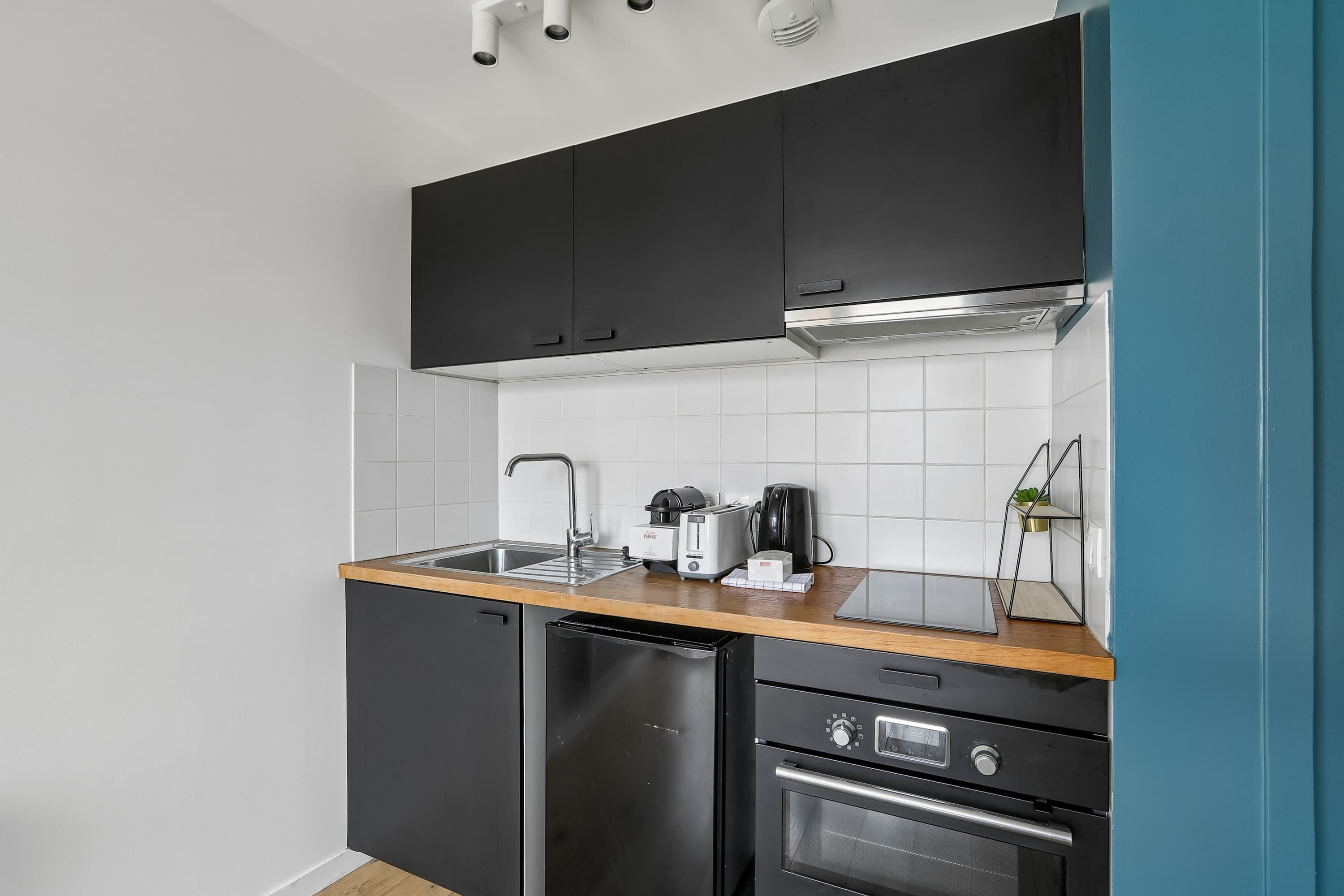 A compact kitchen with black cabinets, a stainless steel sink, a toaster, and a dishwasher.