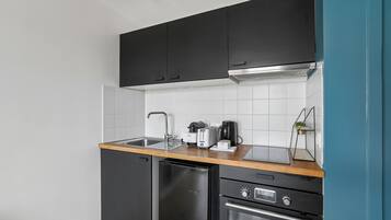 A compact kitchen with black cabinets, a stainless steel sink, a toaster, and a dishwasher.