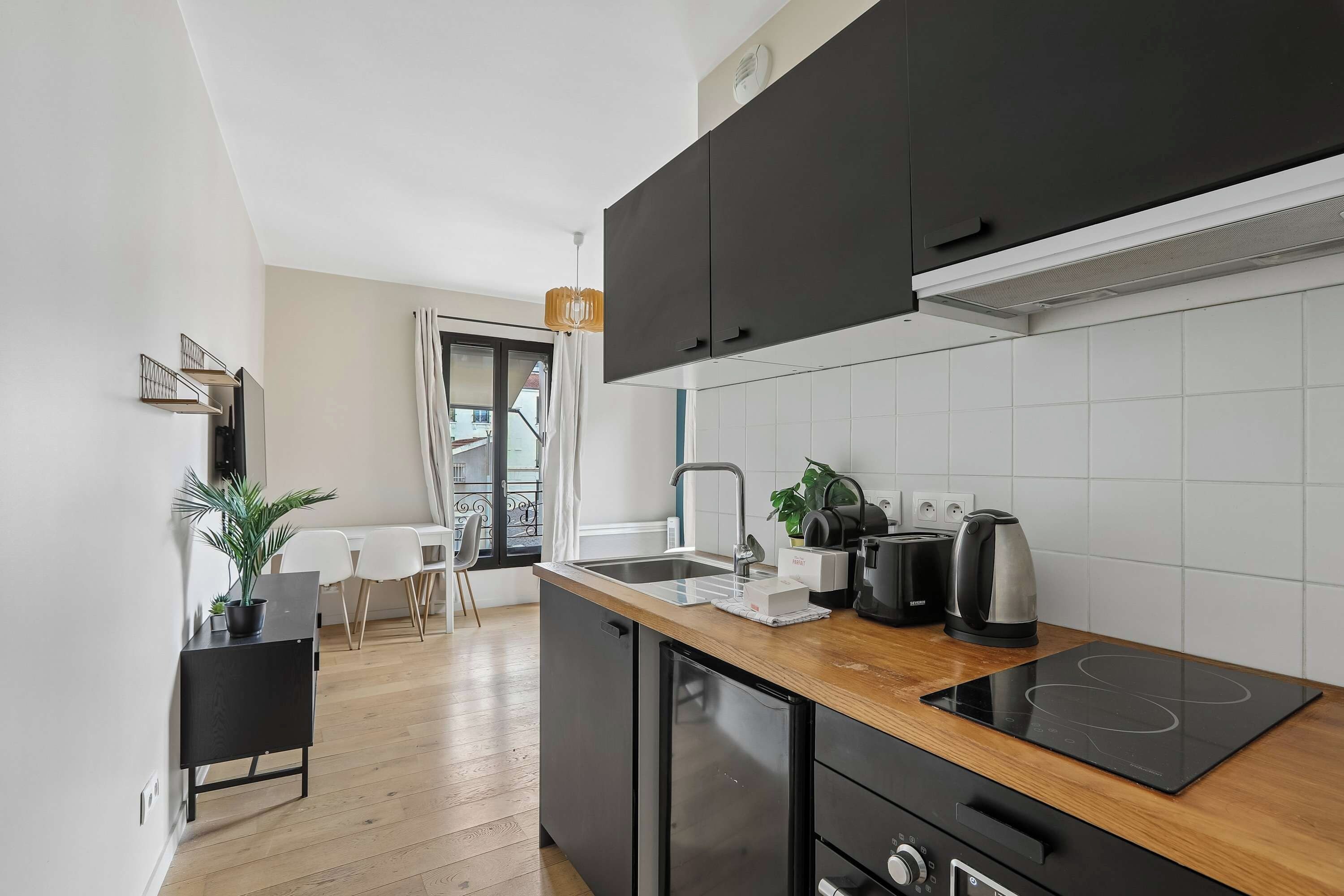 A modern kitchen with black cabinets, a wooden countertop, and a built-in induction cooktop.