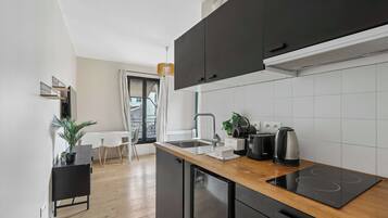 A modern kitchen with black cabinets, a wooden countertop, and a built-in induction cooktop.