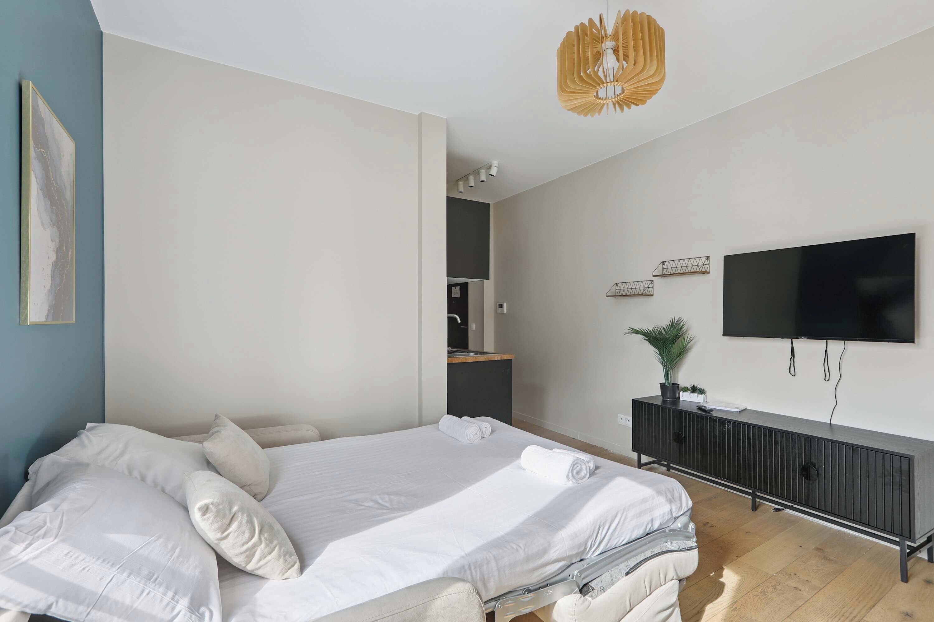 Une chambre à coucher moderne avec un lit, un téléviseur et une plante.
