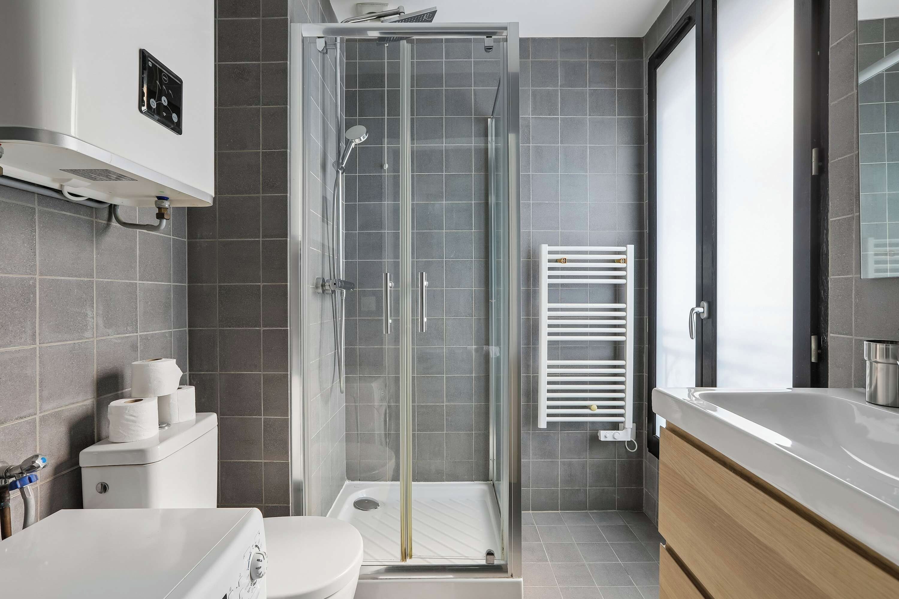 A modern bathroom with a glass-enclosed shower, a white toilet, a sink, and a towel rack.