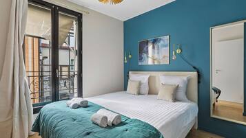Ein Schlafzimmer mit einem Bett, einem großen Fenster, einem Gemälde und einem Spiegel.