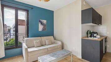 Un apartamento moderno con sofá, banca, cocina y balcón.