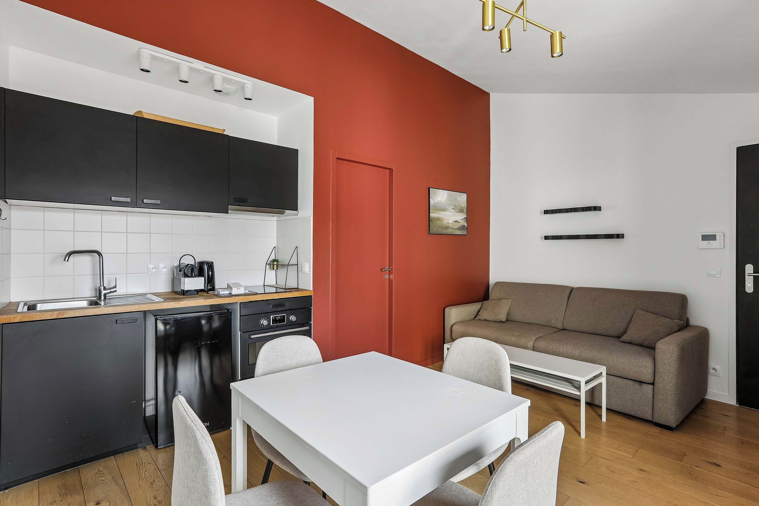 Un espace de vie compact comprenant un coin cuisine, un coin repas et un coin salon.