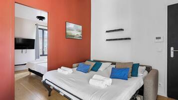 A hotel room with a bed, a TV, a painting, and a door.