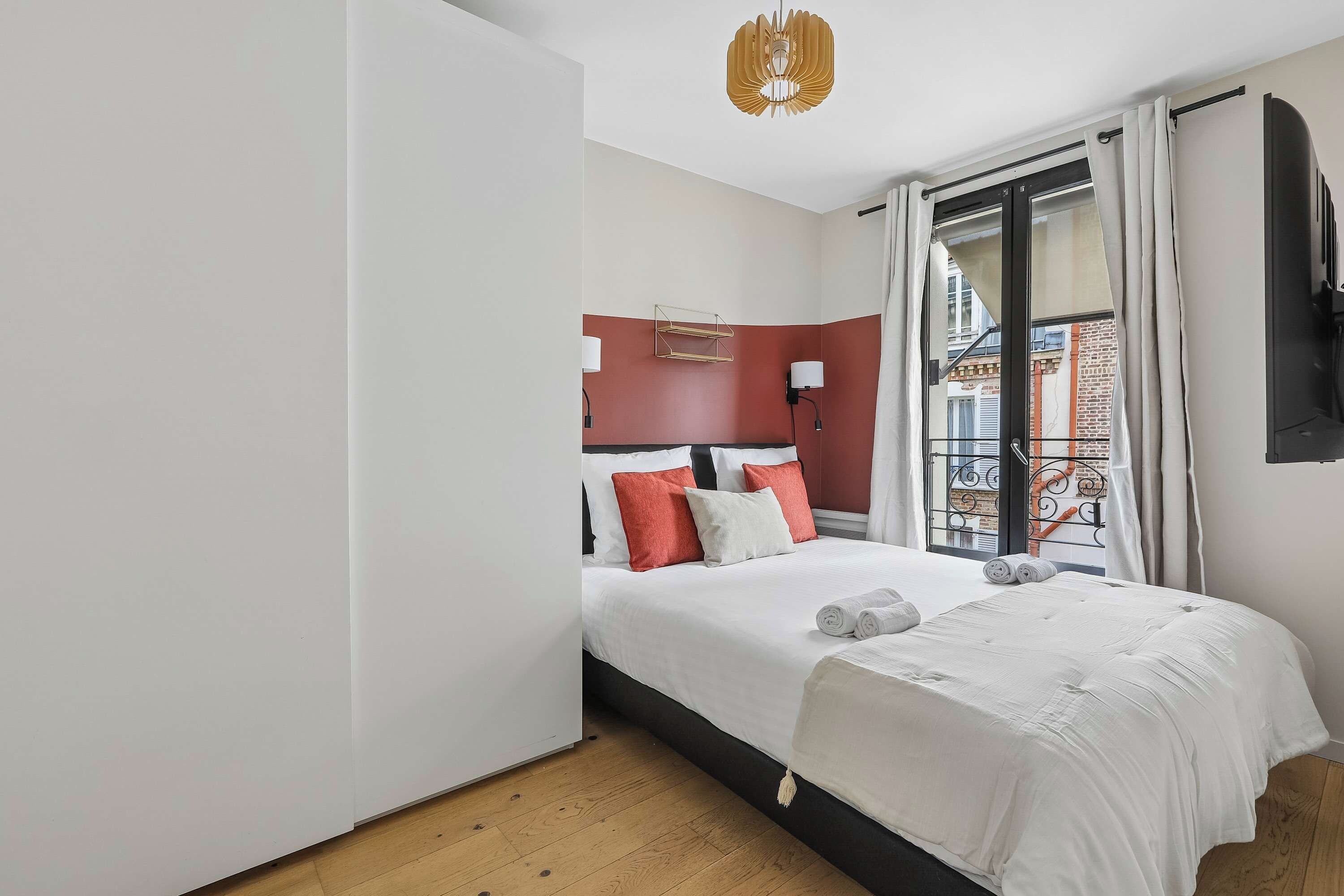Une chambre d’hôtel avec un lit, une table de chevet, une lampe, une fenêtre avec des rideaux et une vue sur l’extérieur.