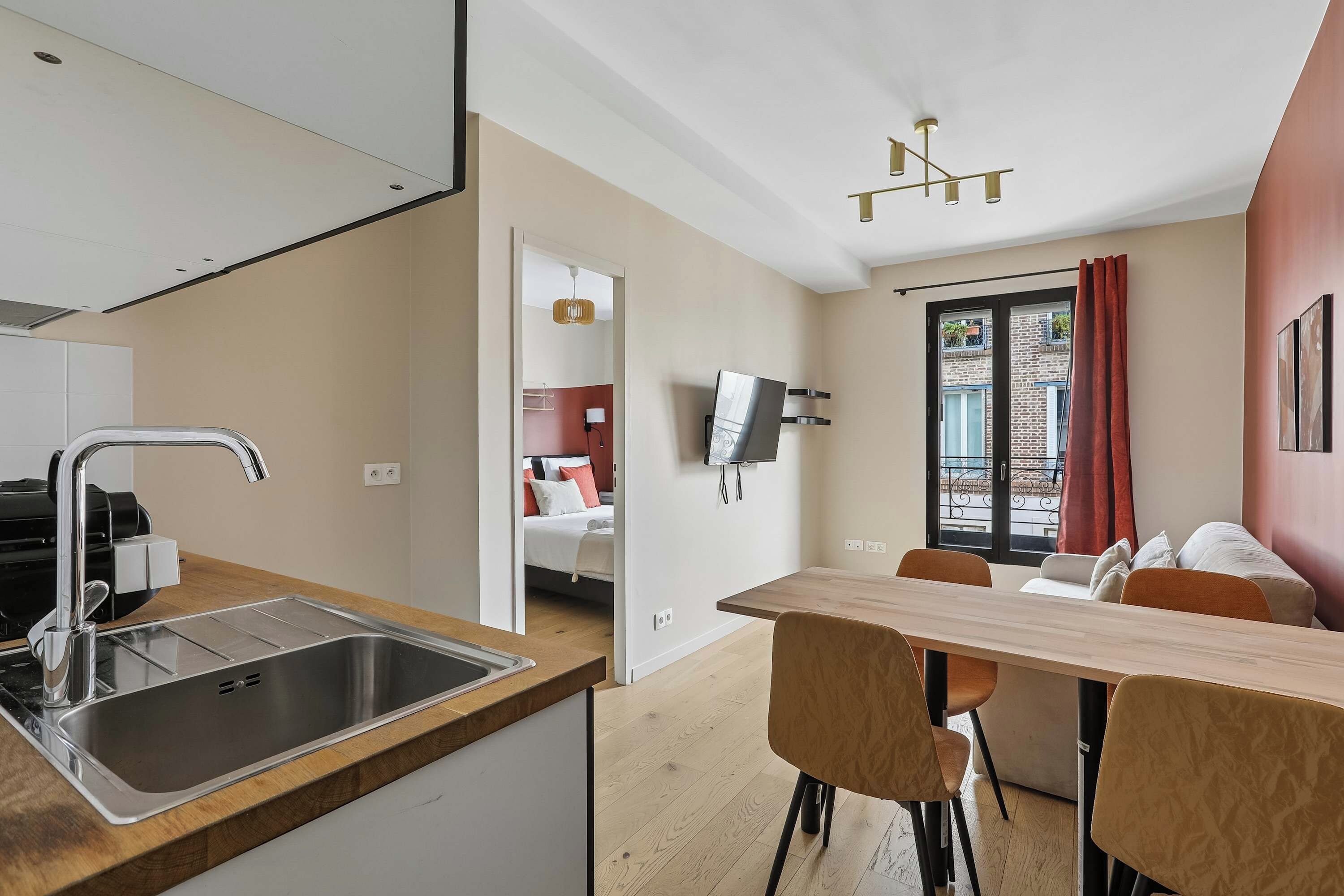 Eine moderne Küche mit Spüle aus Edelstahl und einem Essbereich mit Holztisch und Stühlen.