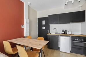 Una cucina compatta con angolo ristoro, dotata di frigorifero, lavastoviglie, fornello e lavandino.