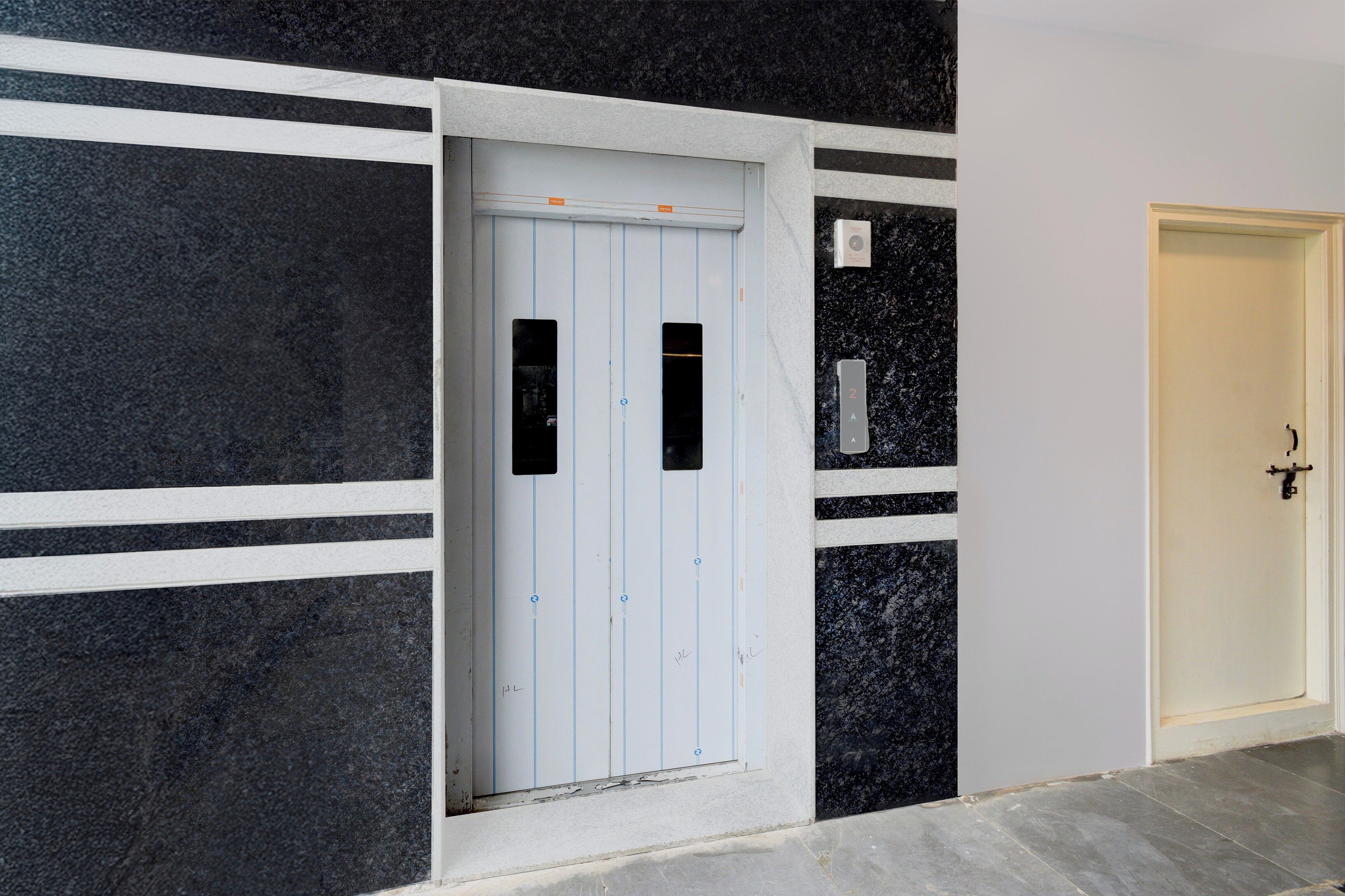 Un pasillo con una puerta blanca, un revestimiento mural a rayas negras y blancas y un suelo de mármol.