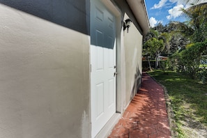 A house with a white door and a brick pathway leading to it.