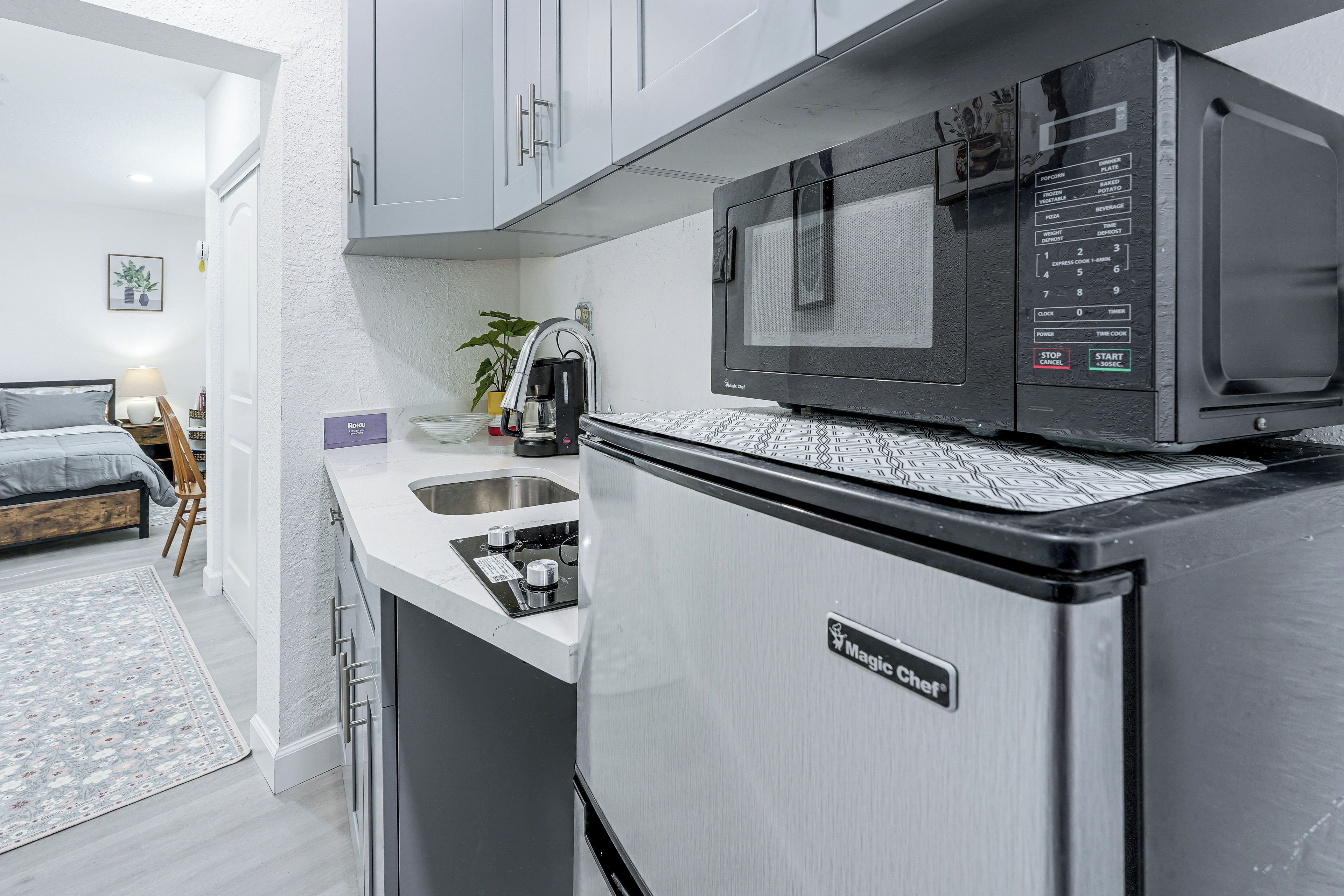 A compact kitchen with a microwave, a refrigerator, and a sink.