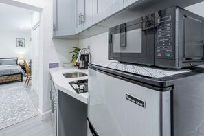 Een kleine keuken met een magnetron, een inbouwoven en een koelkast.