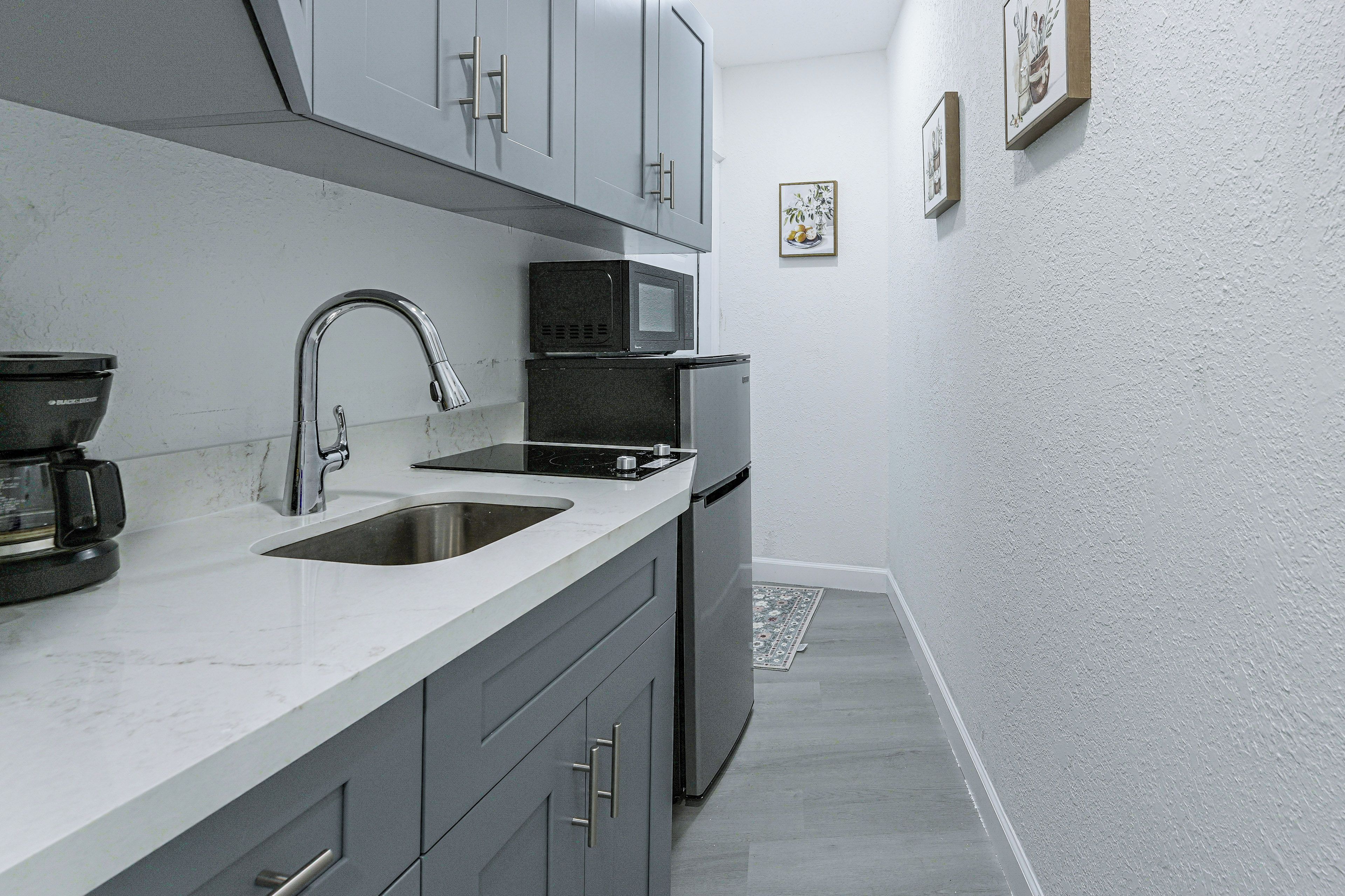 A compact kitchen with a sink, a microwave, and a refrigerator.
